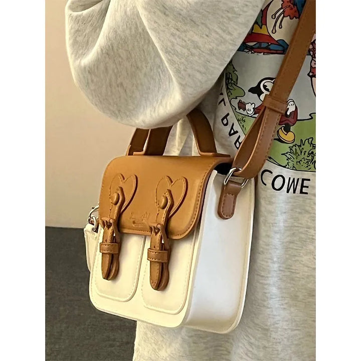 Two-tone women’s shoulder handbag with heart flap and crossbody strap on model