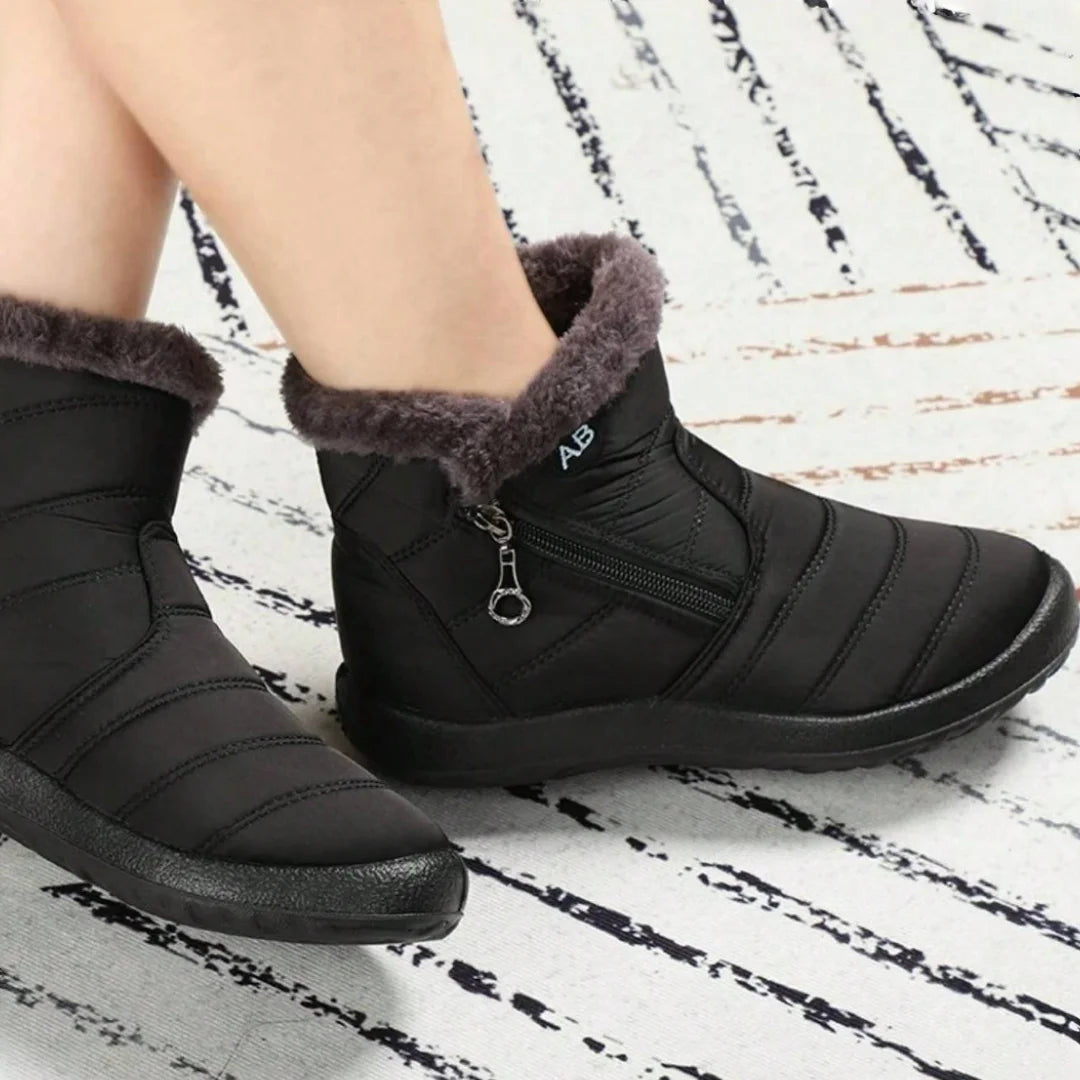 Black winter boots with fur lining worn by a person on a white and black patterned surface