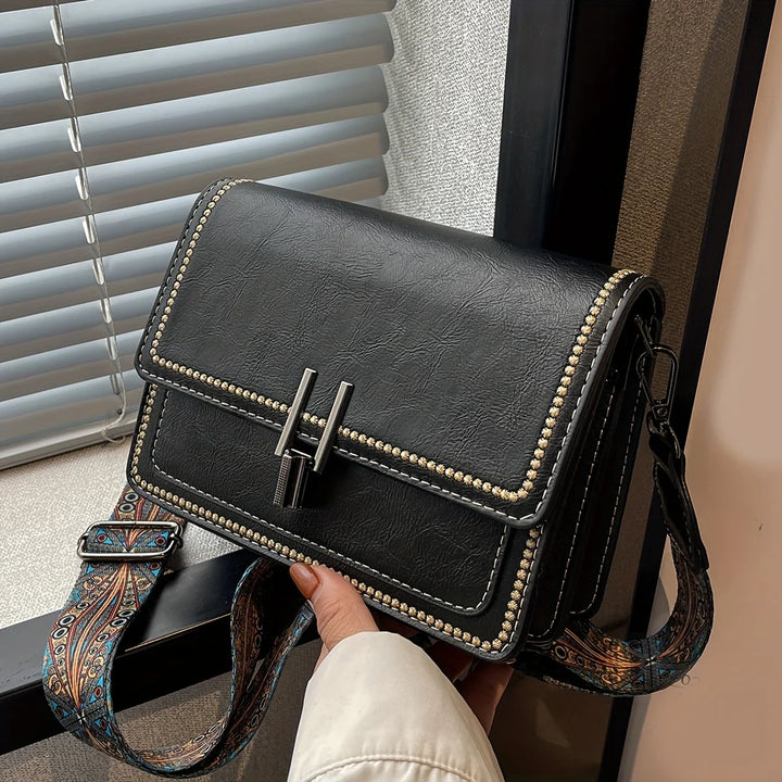 Mini crossbody bag in dark brown with flap lock, beaded trim, and patterned shoulder strap