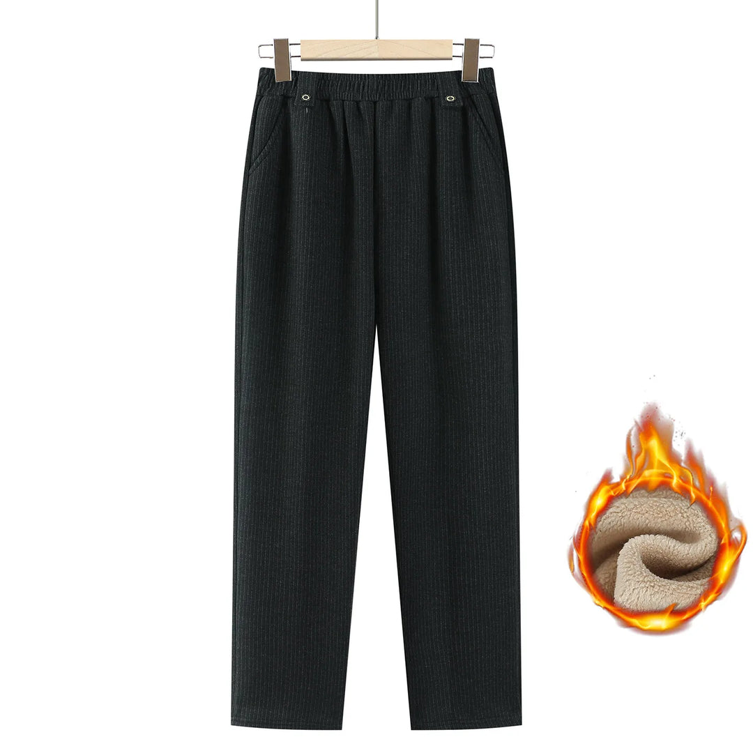 Black ribbed knit cropped pants with an elastic waistband, shown hanging on a wooden hanger against a white background, with a flame graphic revealing a warm beige fleece lining.