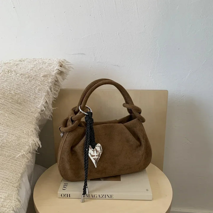 Dark brown suede mini hobo crossbody bag with short handles and heart charm on braided cord.