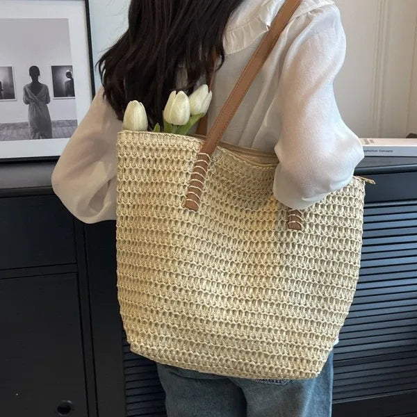 Person holding a woven bag with tulips, standing indoors.