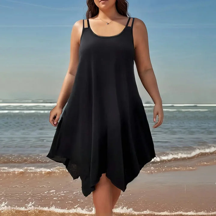 Woman wearing a black dress standing on a beach with ocean waves in the background