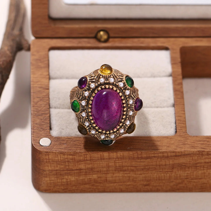 Vintage-style gold oval statement ring with purple center stone and multicolor gems