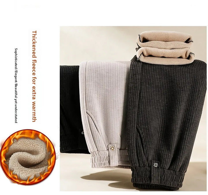 Three pairs of ribbed fleece-lined pants in black, light gray, and dark charcoal are displayed side by side, with the light gray pair folded on top to show the soft fleece lining. A circular graphic on the bottom left shows a close-up of the warm fleece texture with flame-like heat lines, and text on the left describes the thickened fleece for extra warmth.