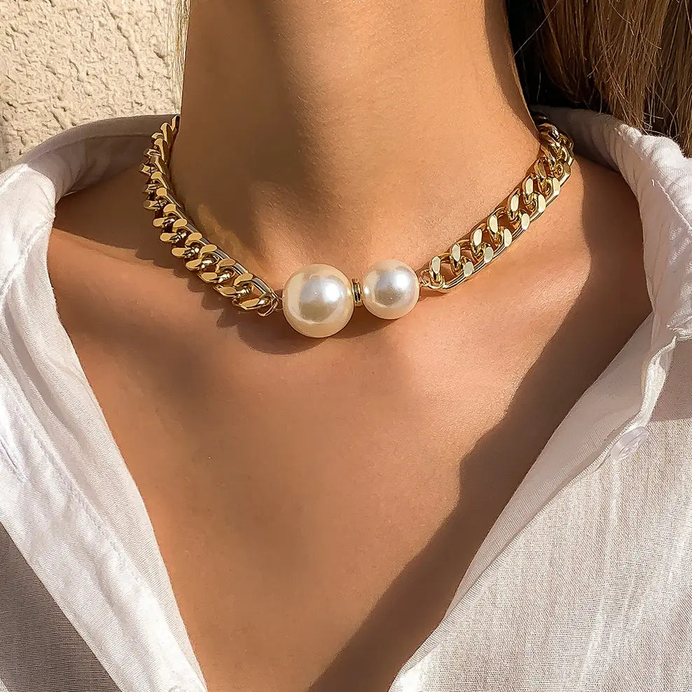 Gold chain necklace with pearls worn by a person against a neutral background