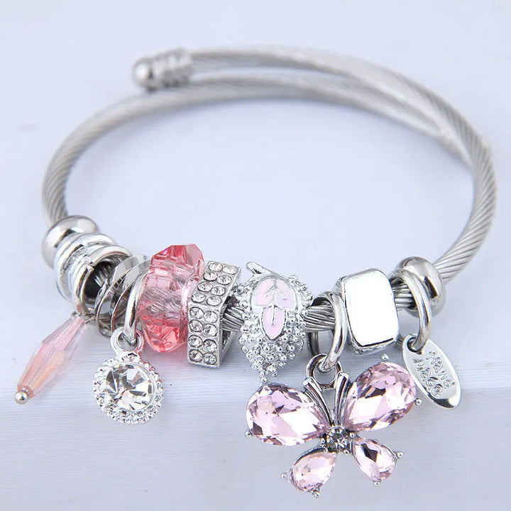 Stainless steel cuff bangle with pink crystal butterfly charms, heart charm, and dangles
