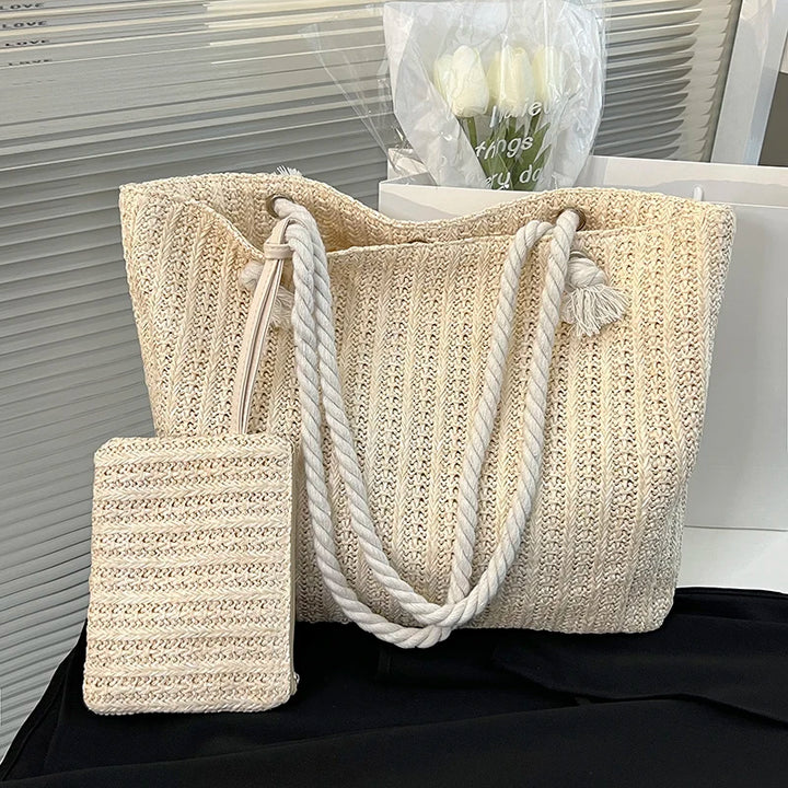 Beige woven tote bag with rope handle on a black surface