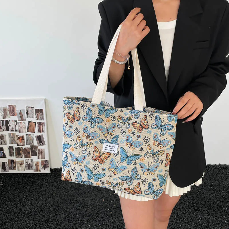 Canvas tote bag with blue butterfly floral print held by a person