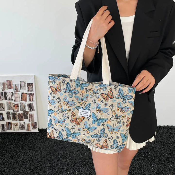 Canvas tote bag with blue butterfly floral print held by a person