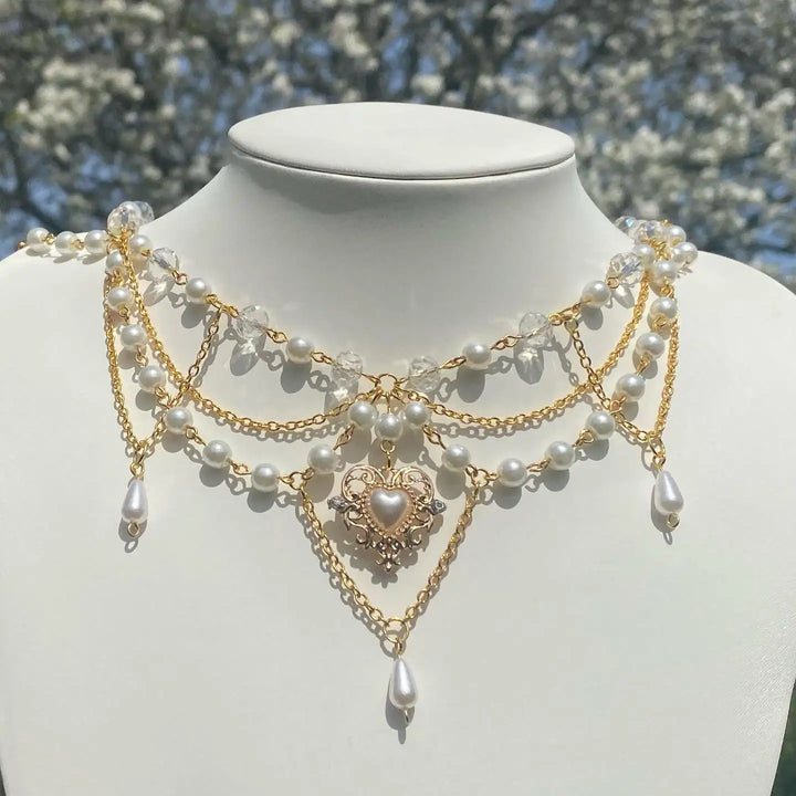 Ivory pearl and gold-tone multi-strand necklace on bust with heart pendant and dangles