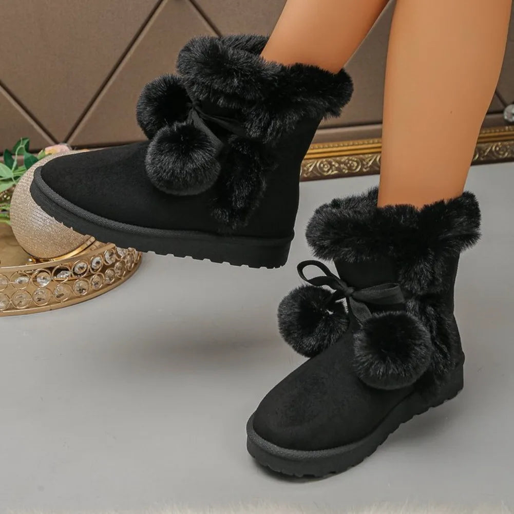 Black faux fur ankle boots with pom-poms and bow details, shown on a doll's legs against a neutral indoor background.