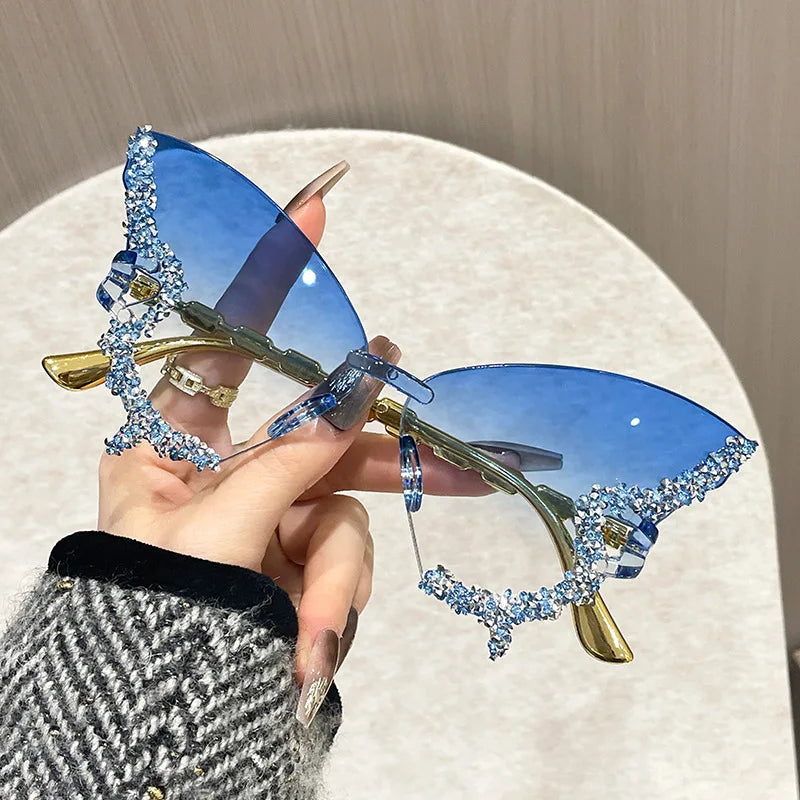 Sunglasses with blue lenses and decorative embellishments held by a hand.