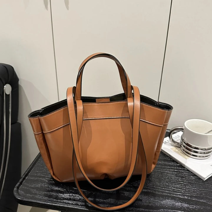 Brown handbag on a black surface with a neutral background
