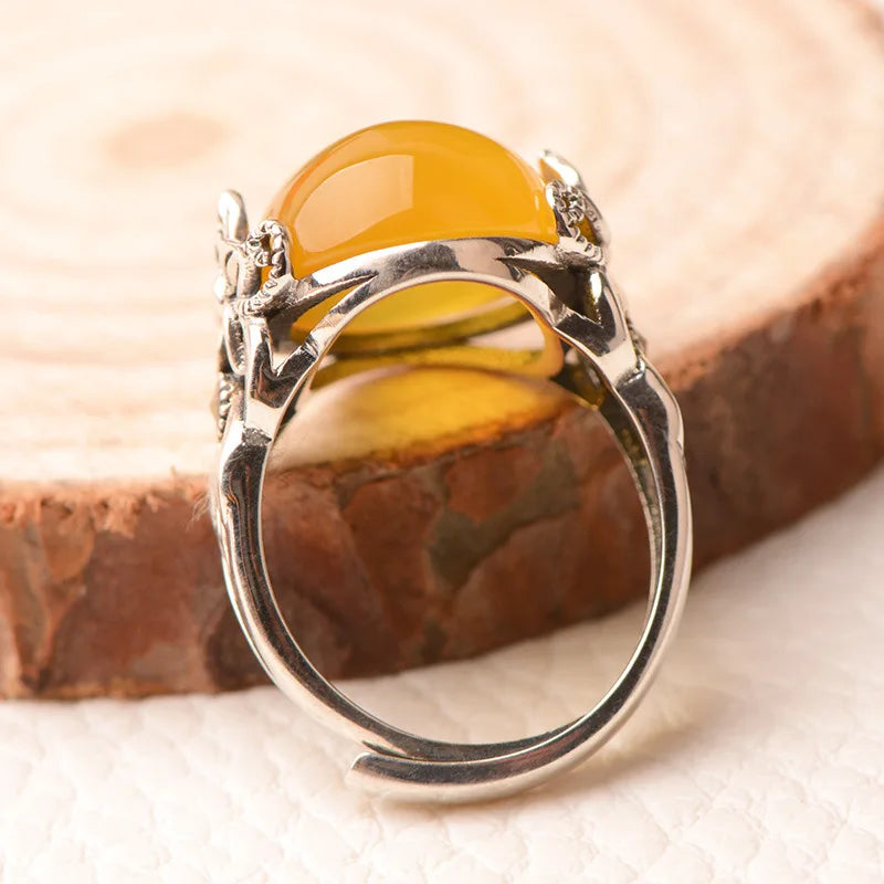 Silver ring with a yellow gemstone on a wooden surface