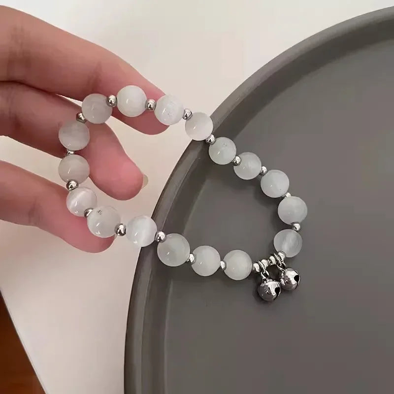 White beaded elastic bracelet with small bell charm and star dangle