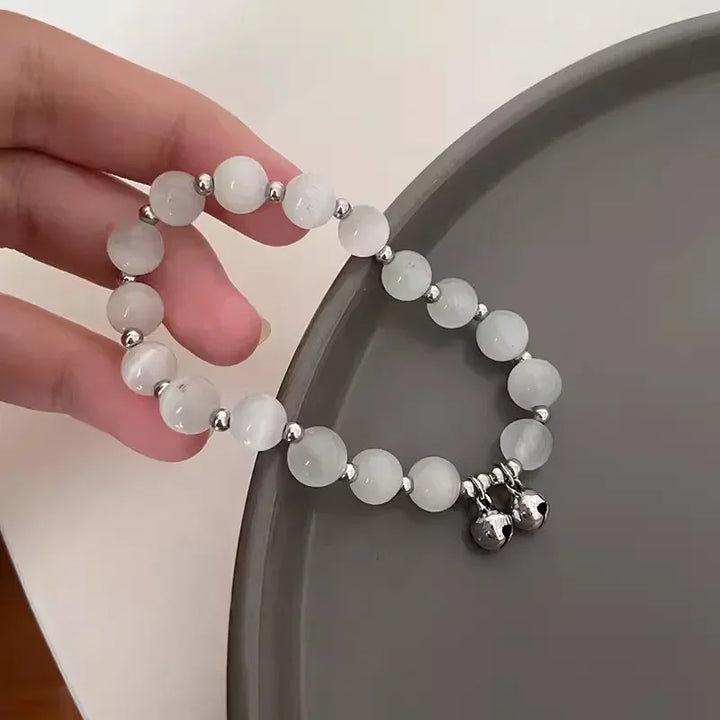 White beaded elastic bracelet with small bell charm and star dangle