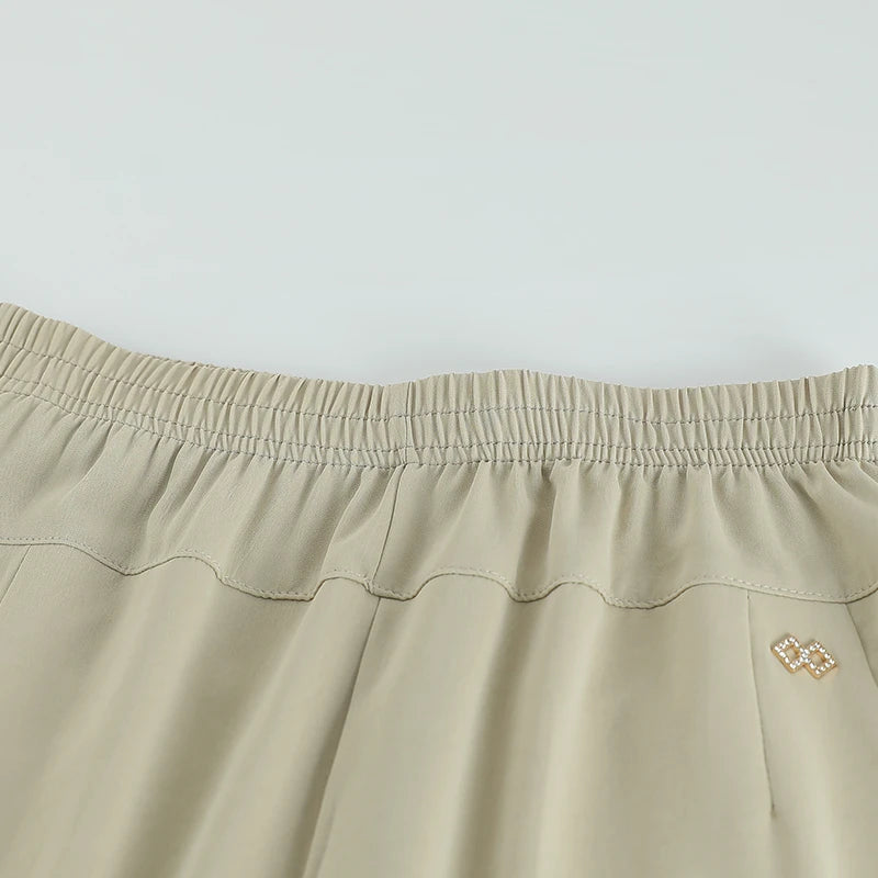Close-up of beige pants with a gathered elastic waistband and angled pockets