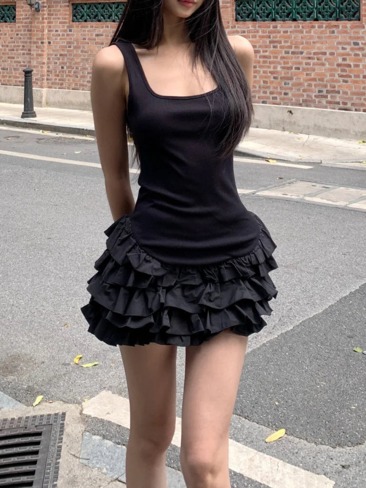 Woman wearing a black sleeveless top and ruffled skirt on a street.