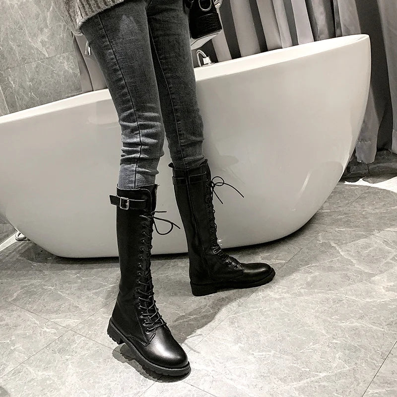 Person wearing black lace-up boots and gray jeans standing in front of a white bathtub.