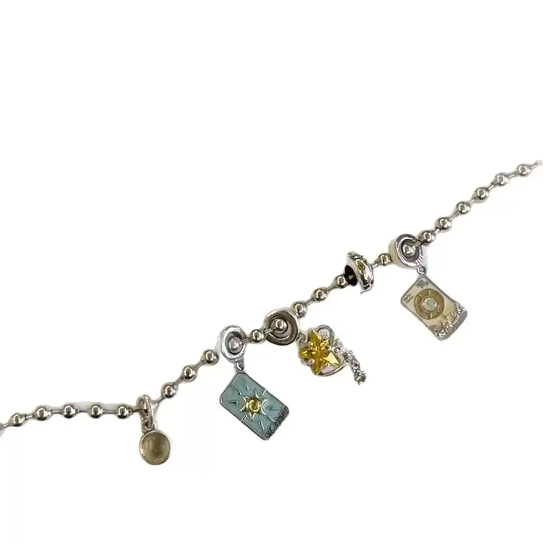 Silver charm bracelet held over a blue jewelry box with star patterns.