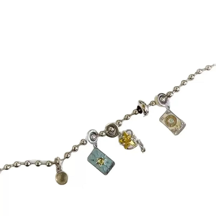 Silver charm bracelet held over a blue jewelry box with star patterns.