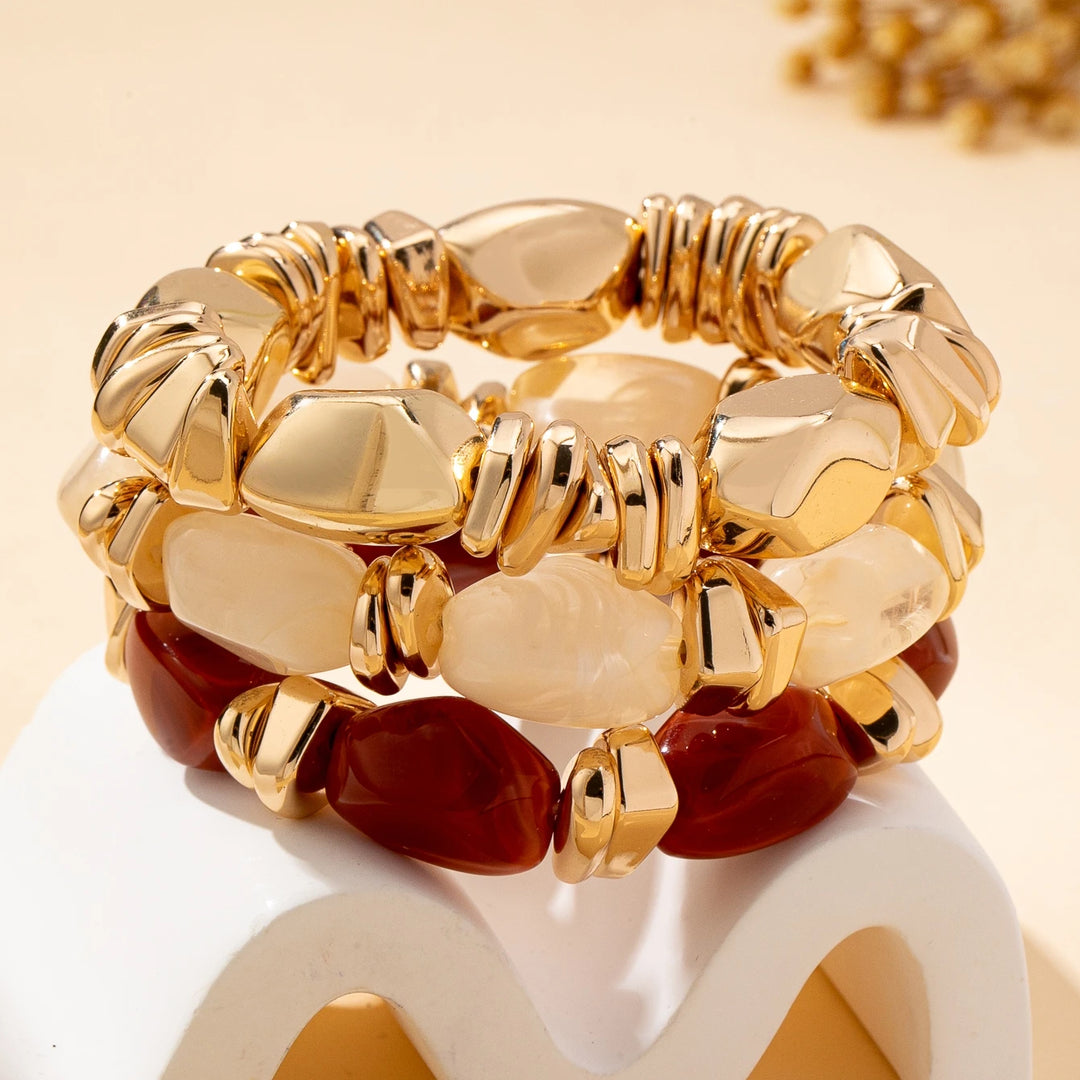 Stacked gold-tone acrylic bead bracelets with cream and deep red irregular beads