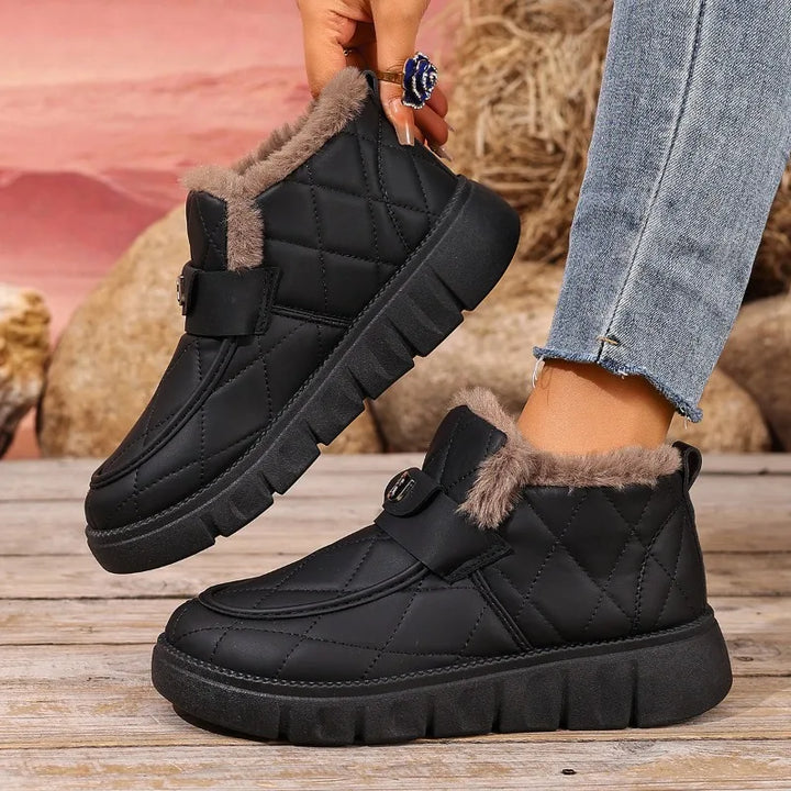 Black quilted ankle boots with faux fur collar and hook-loop strap closures worn with jeans