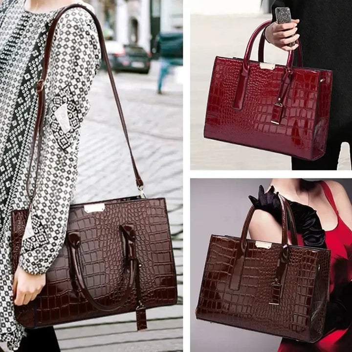 Crocodile-pattern leather tote handbag with top handles and shoulder strap, carried outdoors.