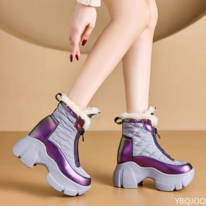 Purple and gray platform boots with white fur lining worn by a person on a beige background
