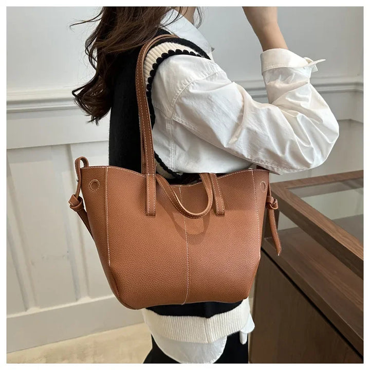 Person holding a brown leather handbag indoors