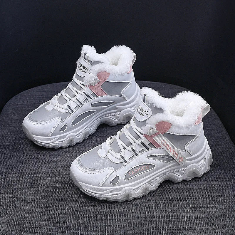 A pair of white and gray mid-height winter sneakers with white faux-fur lining and pink accents, displayed on a dark gray textured surface against a black background.
