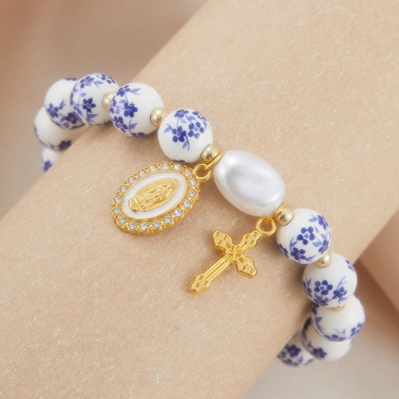 Bracelet with floral beads and gold charms on a wrist against a beige background