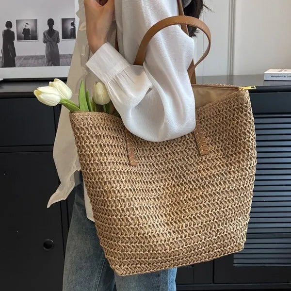Person holding a woven bag with flowers, wearing a white shirt and jeans, in an indoor setting.