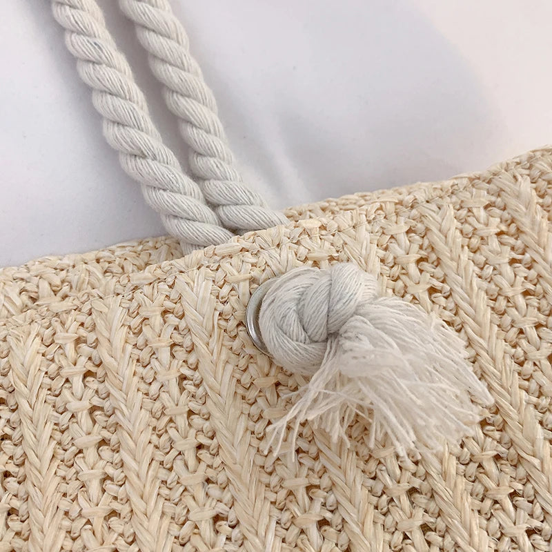 Close-up of a woven bag with rope handles and tassel on a light background