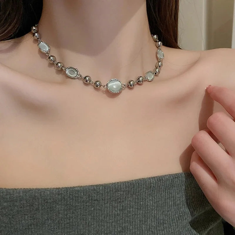 Necklace with silver and green beads on a person wearing a gray top.