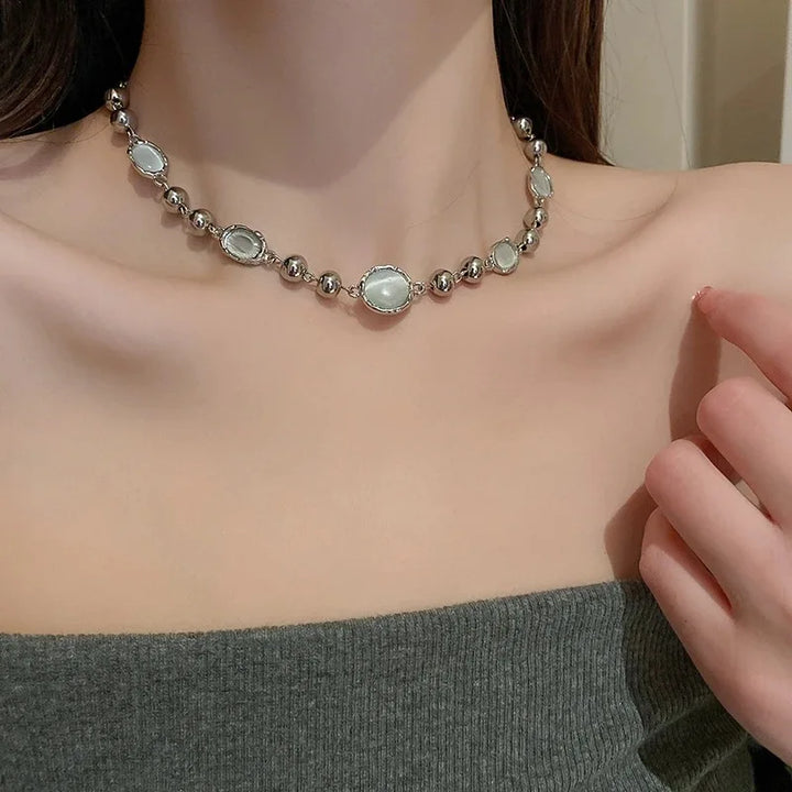 Necklace with silver and green beads on a person wearing a gray top.