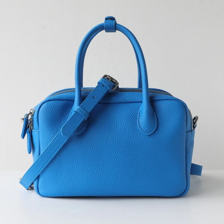 Blue handbag with a strap on a light gray background