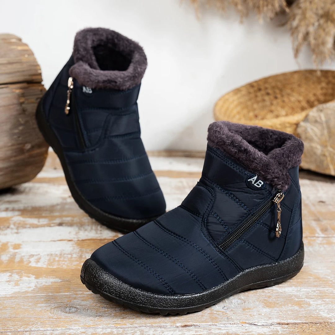 Pair of black winter boots with fur lining on a wooden surface.
