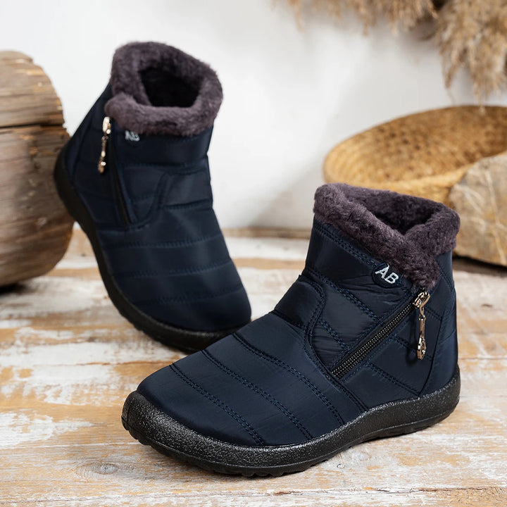 Pair of black winter boots with fur lining on a wooden surface.