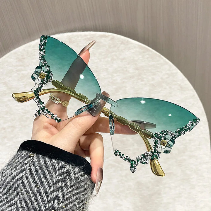 Sunglasses with decorative frame held by a hand on a neutral background
