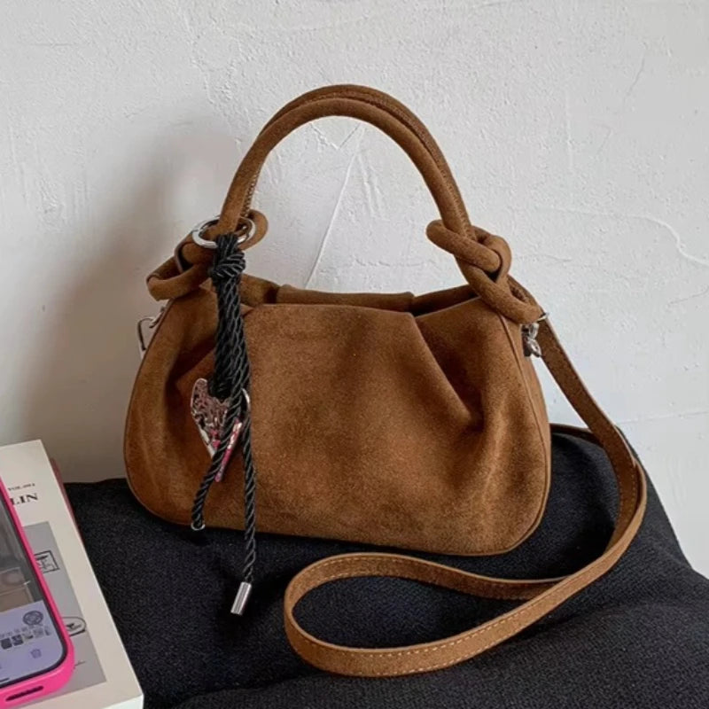 Brown suede mini crossbody hobo bag with short handles and black braided charm cord.