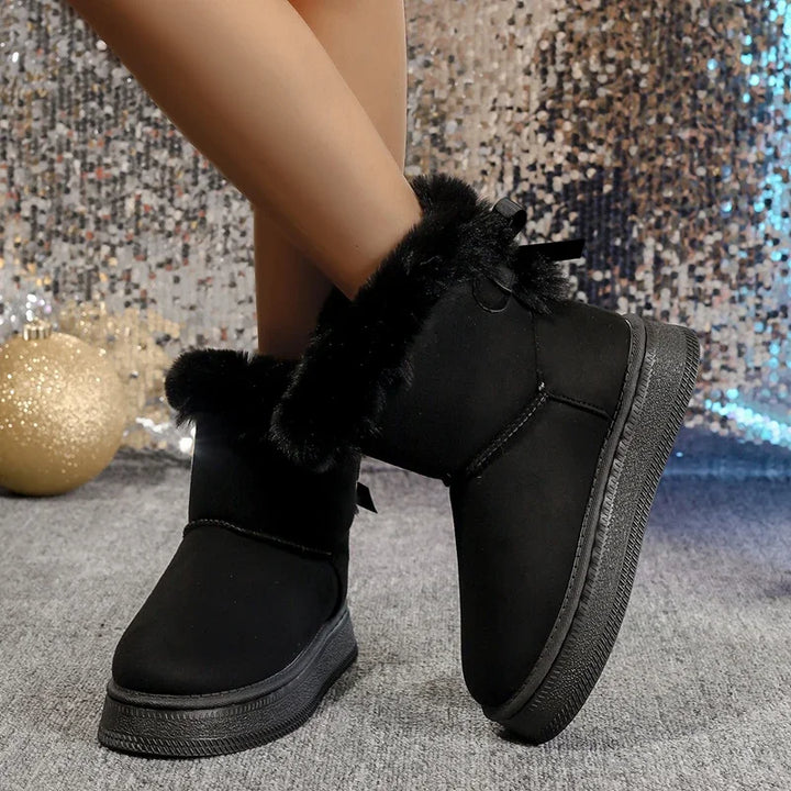 Black winter snow boots with faux fur trim, round toe, and bow detail on the ankle