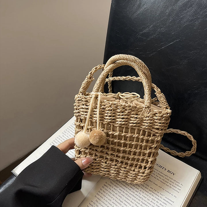 Knit straw bucket crossbody bag in khaki with pom-pom charms and braided handles