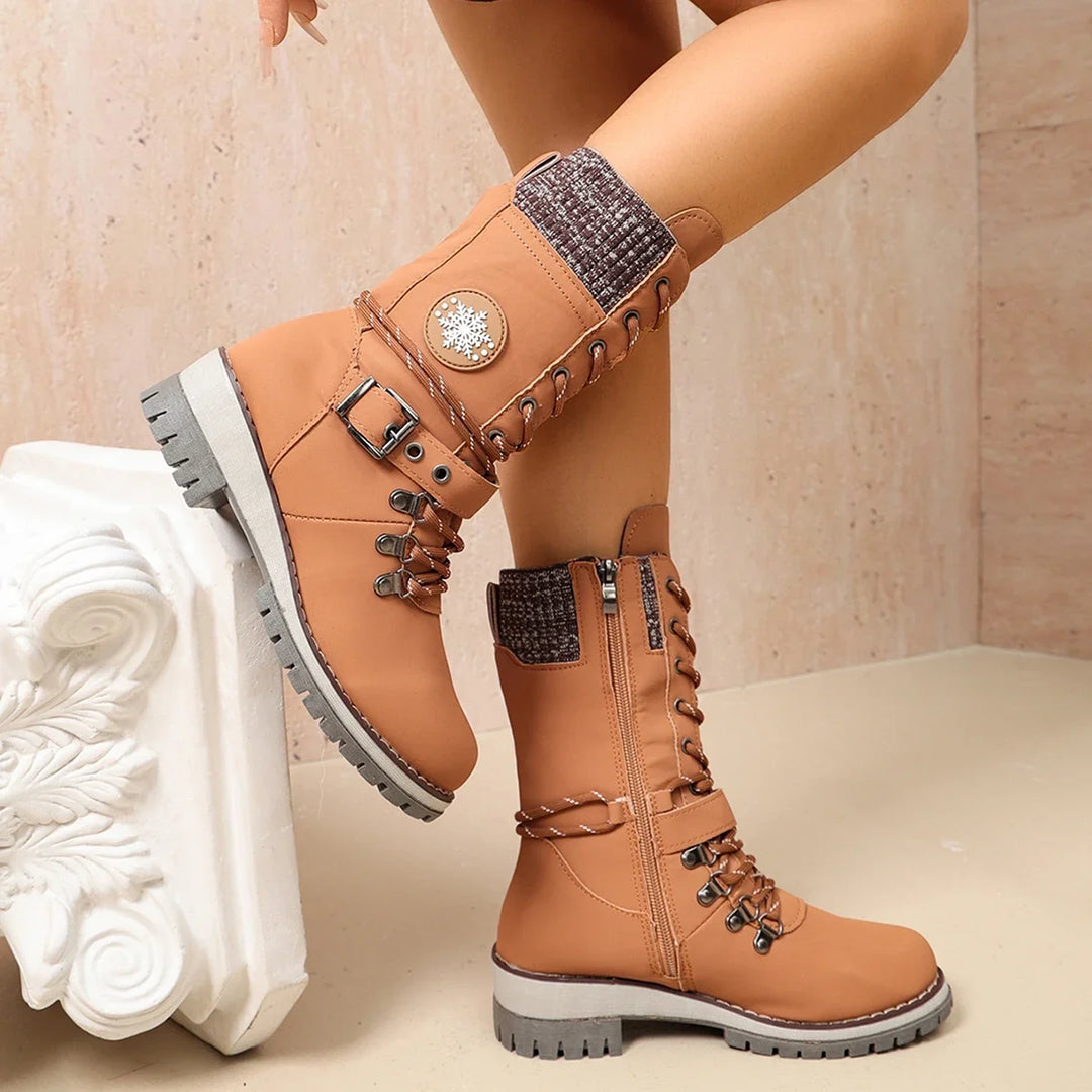 Women’s tan lace-up winter boots with side knit panel, buckle strap, and rugged sole.