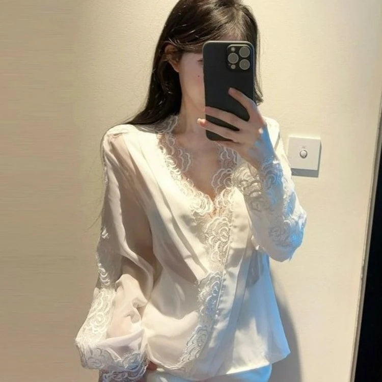 Person wearing a white lace top taking a mirror selfie.