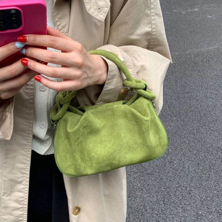 Light green suede mini crossbody hobo bag with short handles and drawstring closure.