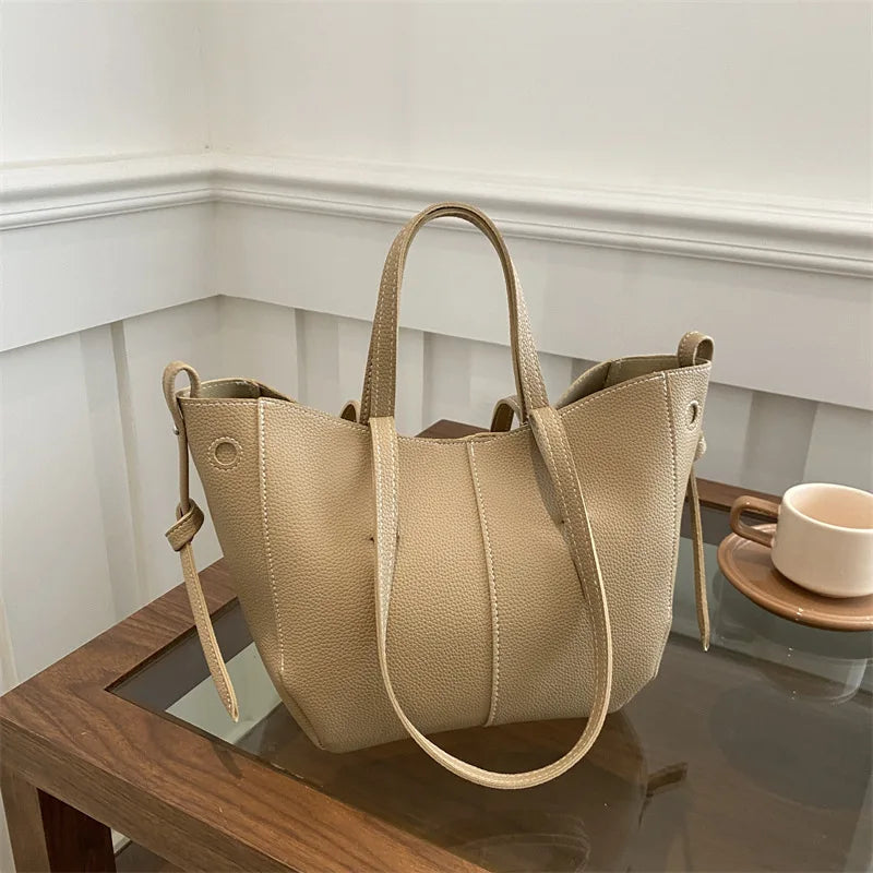 Beige handbag on a reflective surface with a neutral background