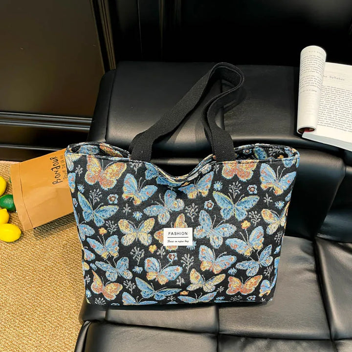 Canvas tote bag with dark blue butterfly floral print and black handles