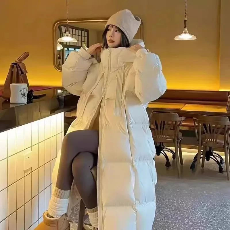 Person wearing a long white puffer coat in a cozy indoor setting.